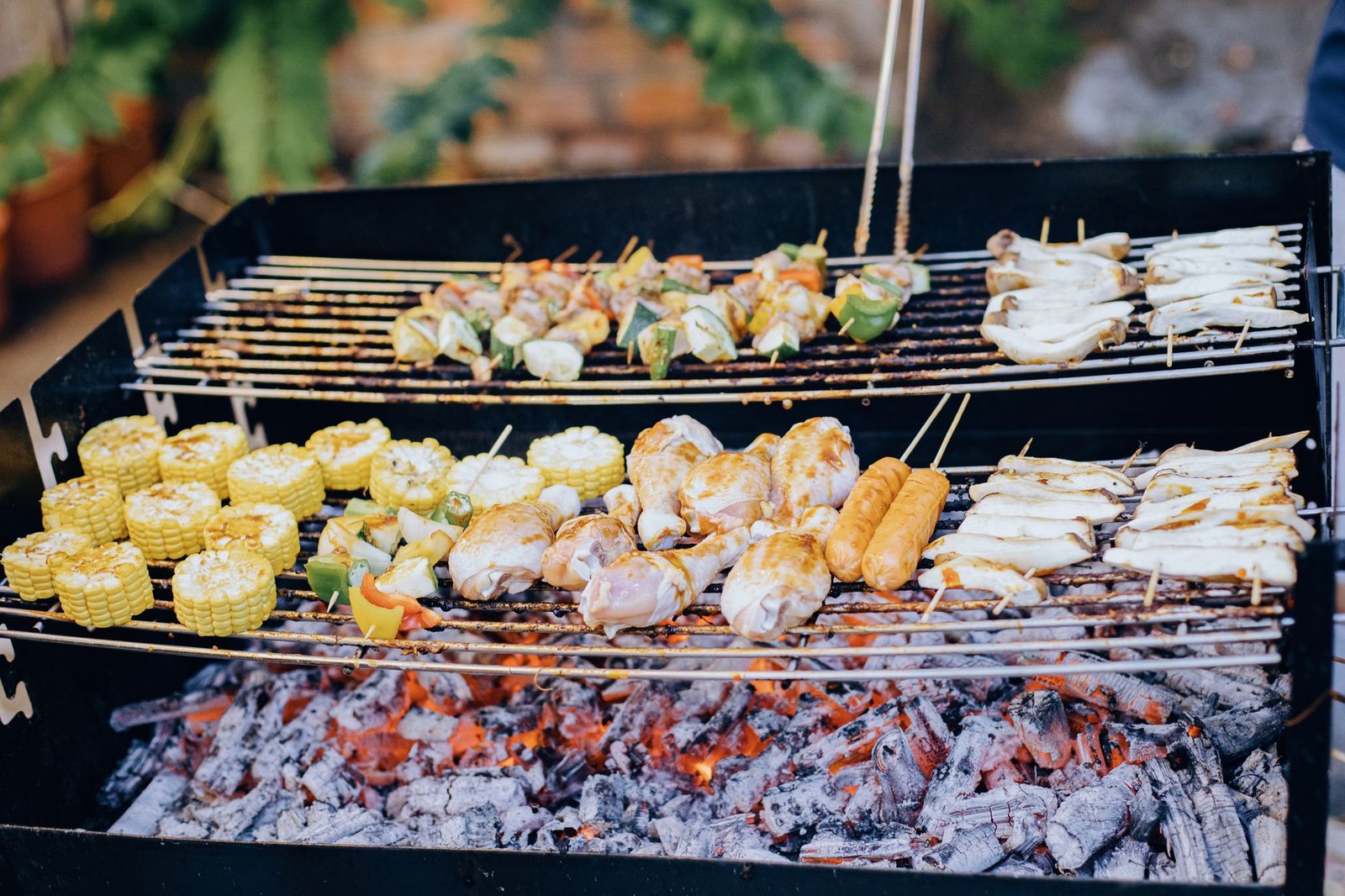 Brasas de carbón bajo una parrilla con maíz, pollo y brochetas (foto ilustrativa de brasas, no de un barril)