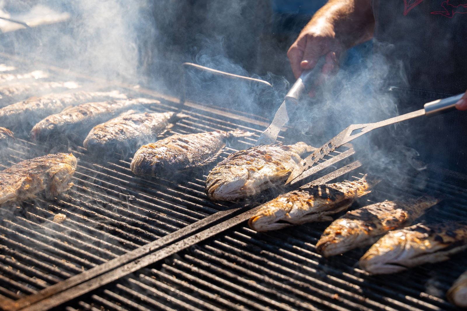 Pescados enteros sobre la rejilla caliente, volteados con una espátula ancha